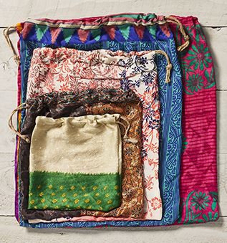 May include: Set of five colorful fabric drawstring bags, nested inside each other. The bags are made from recycled saris and feature various floral and geometric patterns.