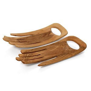 May include: Two wooden salad servers shaped like hands with finger-like prongs. The servers are made of light brown wood with a natural grain pattern.