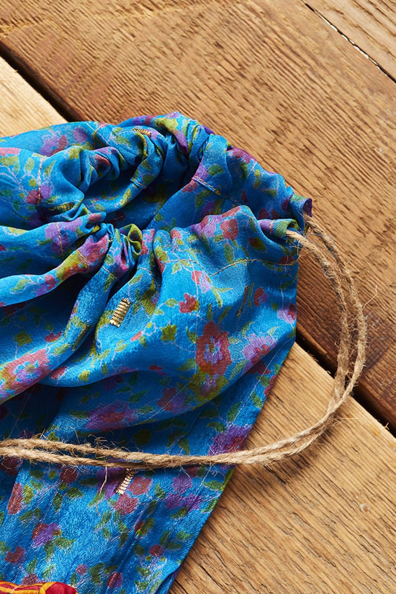 May include: A blue drawstring bag with a floral pattern and a brown cord. The bag is made of a soft, silky fabric.