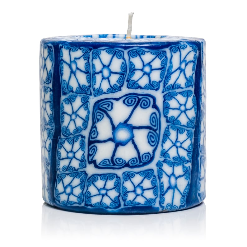 May include: A blue and white candle with a decorative floral pattern. The candle is cylindrical and has a white wick.