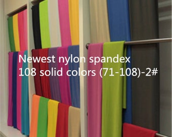 Puede incluir: Una pared con 108 muestras de tela de color sólido, etiquetadas como "Newest nylon spandex 108 solid colors (71-108)-2#", dispuestas en filas en una pared blanca.