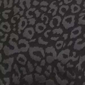 Pode incluir: Tecido preto com padrão de leopardo cinza.