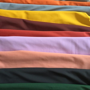 May include: A stack of fabric swatches in various colors, including light blue, green, orange, yellow, brown, red, purple, pink, black, dark green, and brown.