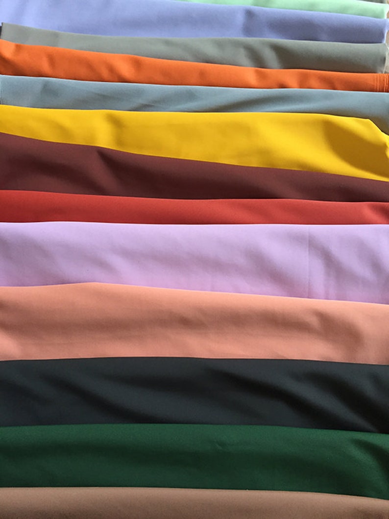 May include: A stack of fabric swatches in various colors, including light blue, green, orange, yellow, brown, red, purple, pink, black, dark green, and brown.