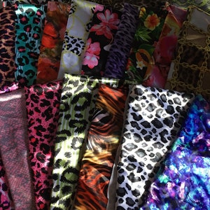 May include: A collection of colorful fabric swatches with various animal print and floral patterns. The fabrics are arranged in a pile, showcasing a variety of textures and designs.
