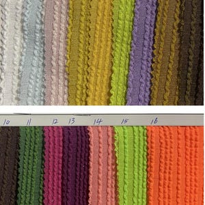 May include: A collection of sixteen fabric swatches in various colors, including white, blue, pink, yellow, green, purple, brown, and orange. Each swatch has a textured, ribbed design. The swatches are numbered 1 through 16.