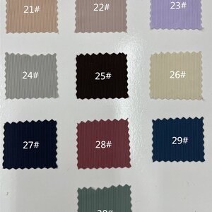 May include: A collection of ten rectangular fabric swatches with pinked edges, each featuring a vertical ribbed texture. The swatches are labeled with numbers 21# through 30# and display a variety of colors including beige, gray, lavender, black, cream, navy, maroon, and sage green.