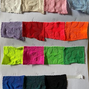 Peut inclure: Une carte de nuanciers avec 15 échantillons de tissus de différentes couleurs et motifs. Le tissu est texturé avec un motif de feuilles. Les échantillons sont numérotés de 1 à 15.