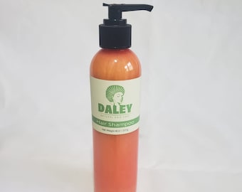 Puede incluir: Una botella de champú para el cabello de color naranja claro con una tapa de bomba negra. La etiqueta es blanca con detalles verdes y dice "Daley Natural Hair Care" y "Hair Shampoo". La botella es de 8 oz / 227g.