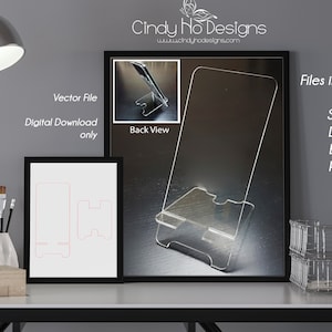 Op de afbeelding: Een digitale download van een telefoonstandaardontwerp. De afbeelding toont een transparante acryl telefoonstandaard met een telefoon erin. De standaard is ontworpen om een telefoon rechtop te houden. De afbeelding toont ook een zwart-witte tekening van het telefoonstandaardontwerp. De tekst op de afbeelding luidt "Vector File, Digital Download only, Back View, Files included, SVG, DXF, EPS, PDF".