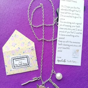 May include: A silver necklace with a charm of a tooth with wings, a small toothbrush charm, a pearl charm, and a "toothpaste" charm. The necklace comes in a small envelope with a note that says "Special delivery from The Tooth Fairy". The note also says "Dear Sweet Friend, Oh, I hope you like this adorable little gift that I have left for you today. I'm so excited to give it to you. You are doing such a great job of keeping your teeth clean and shiny and I am so proud of you that I wanted to leave something extra special! Keep up with the awesome teeth cleaning and show off your beautiful smile! Love Annabelle Tooth Fairy"
