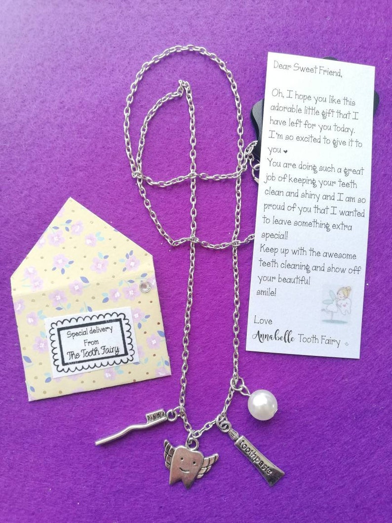 May include: A silver necklace with a charm of a tooth with wings, a small toothbrush charm, a pearl charm, and a "toothpaste" charm. The necklace comes in a small envelope with a note that says "Special delivery from The Tooth Fairy". The note also says "Dear Sweet Friend, Oh, I hope you like this adorable little gift that I have left for you today. I'm so excited to give it to you. You are doing such a great job of keeping your teeth clean and shiny and I am so proud of you that I wanted to leave something extra special! Keep up with the awesome teeth cleaning and show off your beautiful smile! Love Annabelle Tooth Fairy"