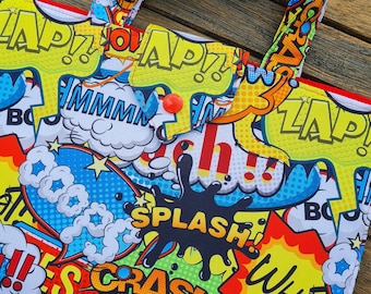 Può includere: Una borsa tote colorata con un design a fumetti che presenta parole come "CRASH", "SPLAS", "POW" e "BAM".