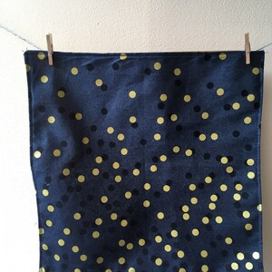 Könnte beinhalten: Eine schwarze Stoffserviette mit goldenen Punkten.