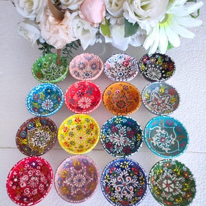 Op de afbeelding: Set van 15 kleine, kleurrijke keramische kommen met ingewikkelde bloem- en geometrische patronen. De kommen zijn perfect om dips, sauzen of snacks te serveren.