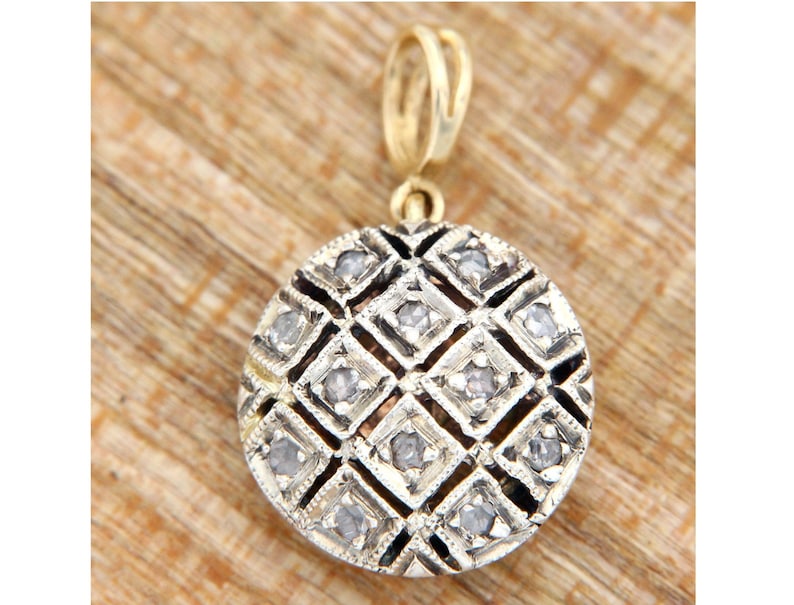 Pode incluir: Um pingente de ouro com um charme redondo prateado. O charme &eacute; decorado com um padr&atilde;o geom&eacute;trico de pequenos diamantes.