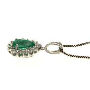 May include: A pear-shaped emerald gemstone pendant set in a white gold halo with smaller diamonds. The pendant is attached to a delicate silver chain.