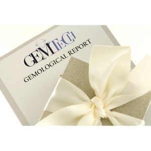 May include: A white gift box with a white satin ribbon tied in a bow. The box is sitting on top of a white card with the text "GEMTECH GEMOLOGICAL REPORT".