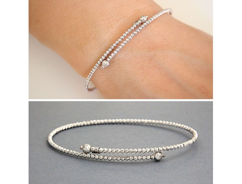 May include: A silver beaded bangle bracelet with a textured finish. The bracelet has a hinged clasp and two small ball accents.