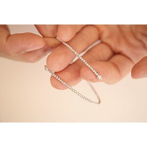 May include: A silver beaded bracelet with a delicate design. The bracelet is made of small, round beads that are evenly spaced.