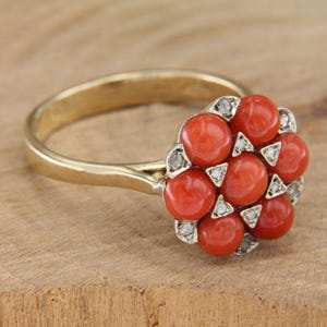 May include: A gold ring with a cluster of red coral stones surrounded by small diamonds.