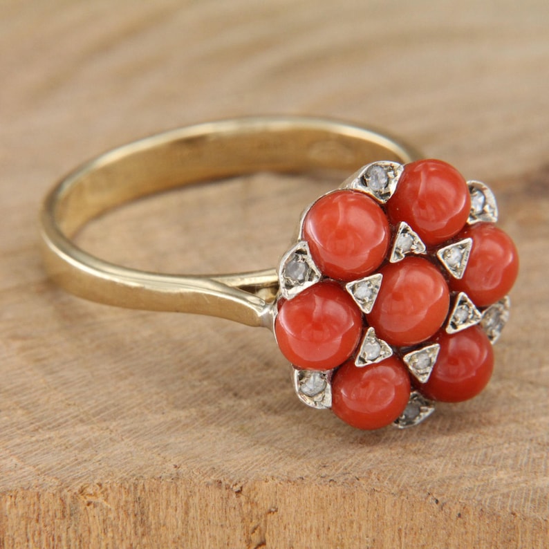 May include: A gold ring with a cluster of red coral stones surrounded by small diamonds.