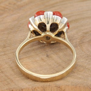 May include: A gold ring with a cluster of red coral stones and a single diamond in the center. The ring is set in a scalloped design.