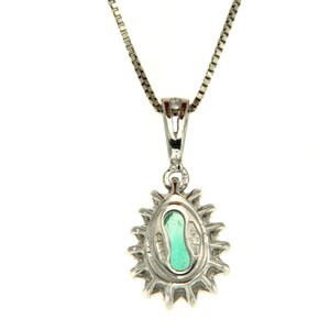 May include: A silver necklace with a pear-shaped green gemstone pendant surrounded by smaller diamonds. The pendant has a detailed design and is set in a silver halo.
