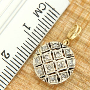 Pode incluir: Um pingente redondo de ouro com um design geom&eacute;trico de pequenos diamantes engastados em uma grade. O pingente mede aproximadamente 2,5 cm de di&acirc;metro e tem um la&ccedil;o na parte superior para prender a uma corrente.