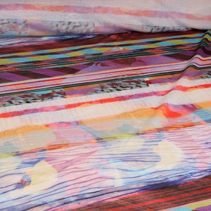 May include: Colorful striped fabric with a white background. The fabric has a variety of colors, including red, orange, yellow, green, blue, purple, and pink. The stripes are of varying widths and are arranged in a random pattern.