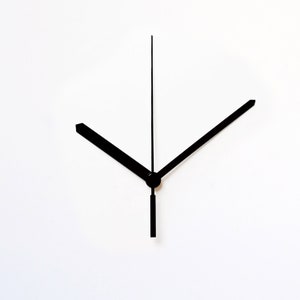 May include: Black clock hands with a long, thin second hand and two shorter hands.