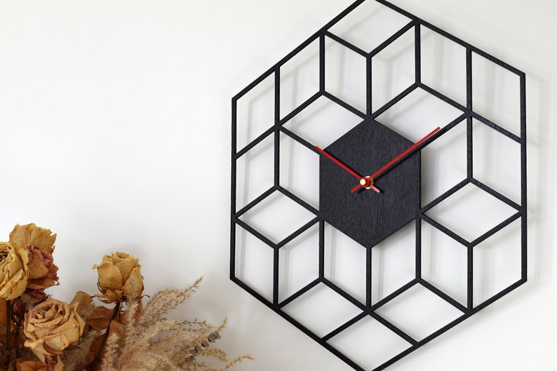 May include: Black geometric wall clock with red hands and a black clock face. The clock is made of wood and has a modern design.