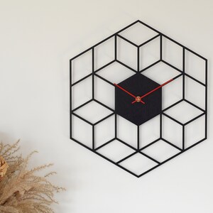 May include: A black geometric clock with red hands and a black face. The clock is shaped like a hexagon and is made up of a series of overlapping cubes.