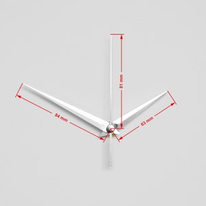 Op de afbeelding: Witte wijzers voor een klok met een gouden middelpunt. De uurwijzer is 81 mm lang, de minutenwijzer 84 mm lang en de secondewijzer 63 mm lang.