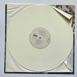 May include: White vinyl record with a black and white label. The label has the text "The Moody Blues From The Bottom Of Their Hearts" and "Impact Line" printed on it. The record is in a white paper sleeve.