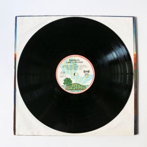 Pu&ograve; includere: Disco in vinile nero con un'etichetta rosa e blu che recita "Emerson, Lake & Palmer" e "Tarkus".