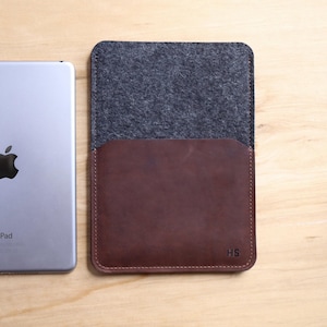 May include: A brown leather and gray felt iPad case with the initials "HS" embossed on the bottom right corner.