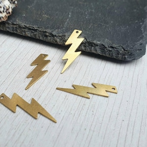 May include: Four gold-colored lightning bolt charms with a hole at the top for attaching to jewelry or other crafts.