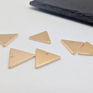 以下が含まれることがあります： 上部に小さな穴が開いた、金色の三角形のチャームが6つ。チャームは平らで、光沢のある仕上げになっています。
