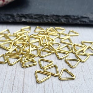 以下が含まれることがあります： 金色の三角形のジャンプリングの山。ジャンプリングは小さく繊細で、ジュエリー作りに最適です。