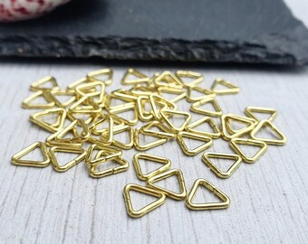 May include: A pile of gold-colored triangle jump rings. The jump rings are small and delicate, and they are perfect for jewelry making.