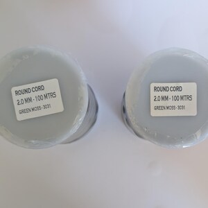 K&ouml;nnte beinhalten: Zwei Spulen mit Rundschnur, jede mit einem Etikett mit der Aufschrift "ROUND CORD 2.0 MM - 100 MTRS GREEN MOSS - 3031".