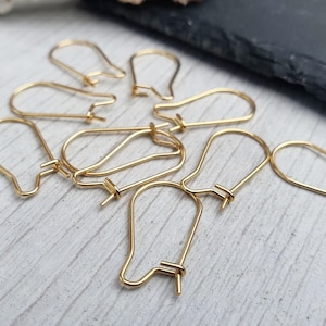 May include: A close-up of eight gold-toned earring hooks. The hooks are made of metal and have a simple, elegant design.