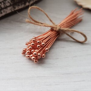 May include: A bunch of copper wire head pins with round heads, tied together with twine.