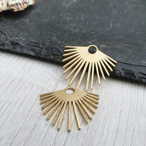 以下が含まれることがあります： ジュエリーやその他のクラフトに付けるための穴が上部にある、金色の金属製のサンバーストチャーム2個