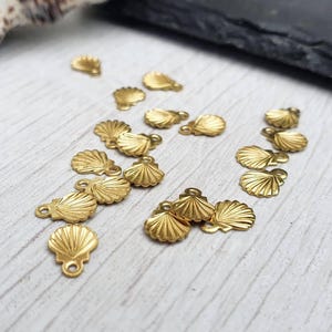 以下が含まれることがあります： 金色の金属製の貝殻チャームのコレクション。ジュエリーやその他のクラフトに付けるためのループが付いています。