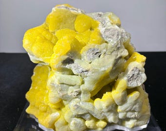 May include: A large, yellow and green Smithsonite specimen with a botryoidal texture. The specimen is displayed on a clear acrylic base with a label that reads "Smithsonite, Lanying, Yunnan, China".