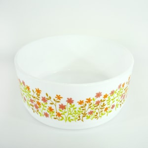Peut inclure: Bol rond blanc avec un motif floral. Le bol présente une bordure de fleurs roses, oranges et vertes. Les fleurs sont disposées le long du bord, créant une bordure décorative. Un article de cuisine vintage.