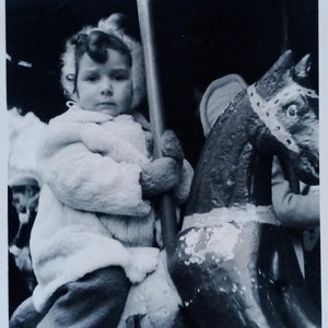 Antigua fotografía en blanco y negro - retrato de un niño en un tiovivo - caballo de tiovivo - foto de película