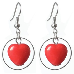 Peut inclure: Une paire de boucles d'oreilles créoles argentées avec un pendentif en forme de cœur rouge.